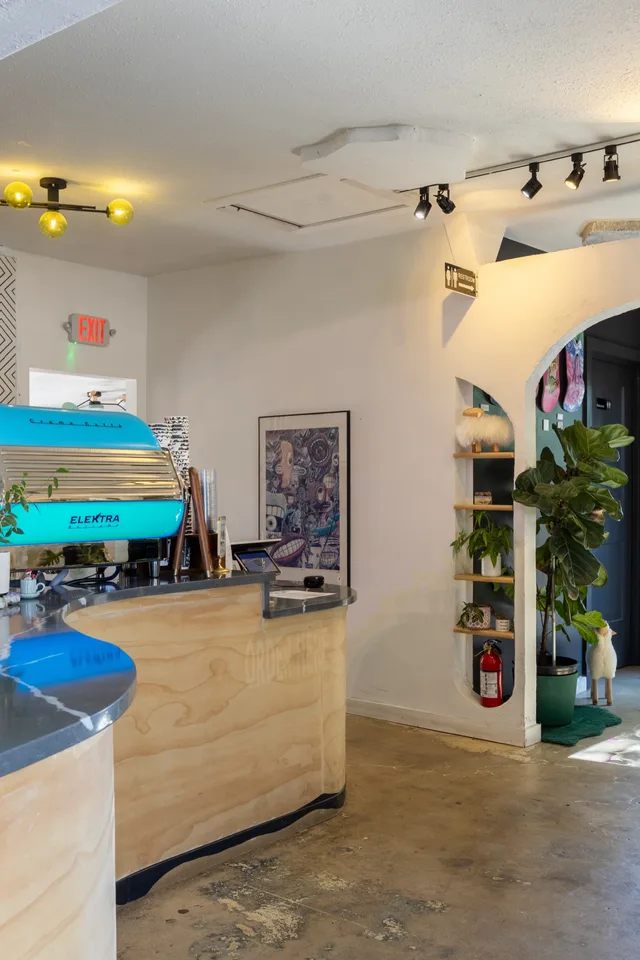 The bar, with the teal counter, plants and a skate deck