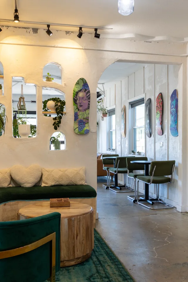 Green velvet lounge seating with skate decks on the wall and plants
